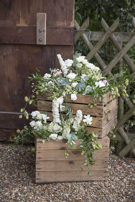 Decoração com arranjo de flores e caixotes de madeira